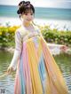 A young girl in a colorful dress standing by the water.