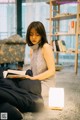 A woman sitting on the floor reading a book.