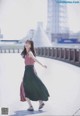 A woman in a pink top and green skirt is walking on a bridge.