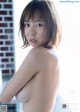 A naked asian woman standing in front of a window.