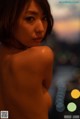 A naked woman standing in front of a city at night.