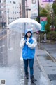 A woman in a blue jacket holding an umbrella in the rain.