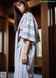 A woman wearing a blue and white striped kimono standing in a room.