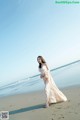 A woman in a long dress standing on a beach.